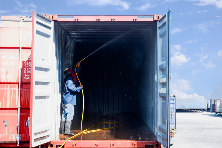 Full length of man cleaning cargo container