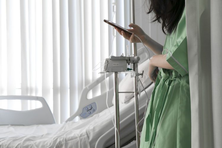 Midsection of woman using mobile phone while standing at hospital