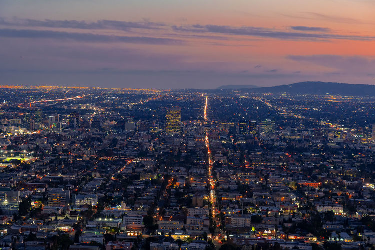 Aerial view of illuminated city buildings during sunset