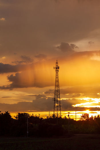 Silhouette electricity pylon on field against sky during sunset