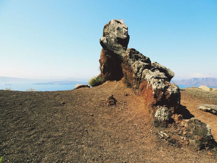 Rock formations on landscape against clear blue sky