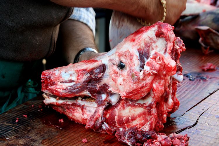 Butcher working on animal head in shop