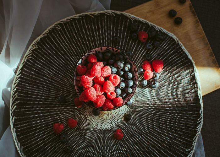 Little bowl with raspberries and blueberries, in a nice background.