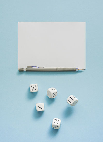 Yahtzee game in progress. rolling dice, pencil and score sheet on a blue background.