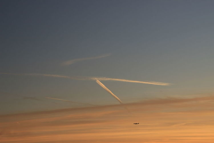 Low angle view of airplane performing smoke stunt during sunset