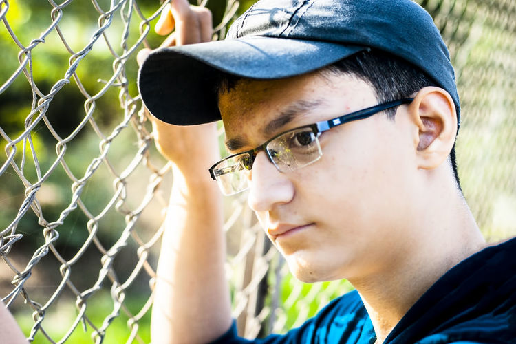 Close-up of thoughtful boy by fence