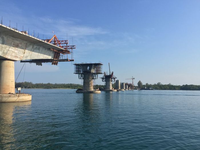 Low angle view of under construction bridge over lake against sky