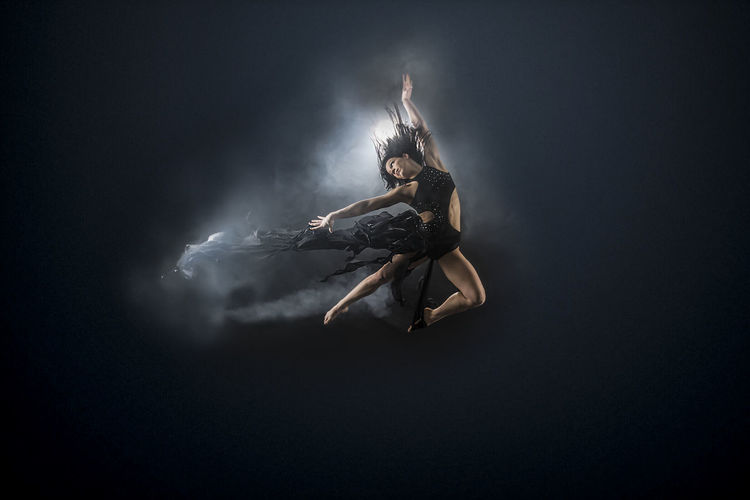 Full length of female dancer against black background