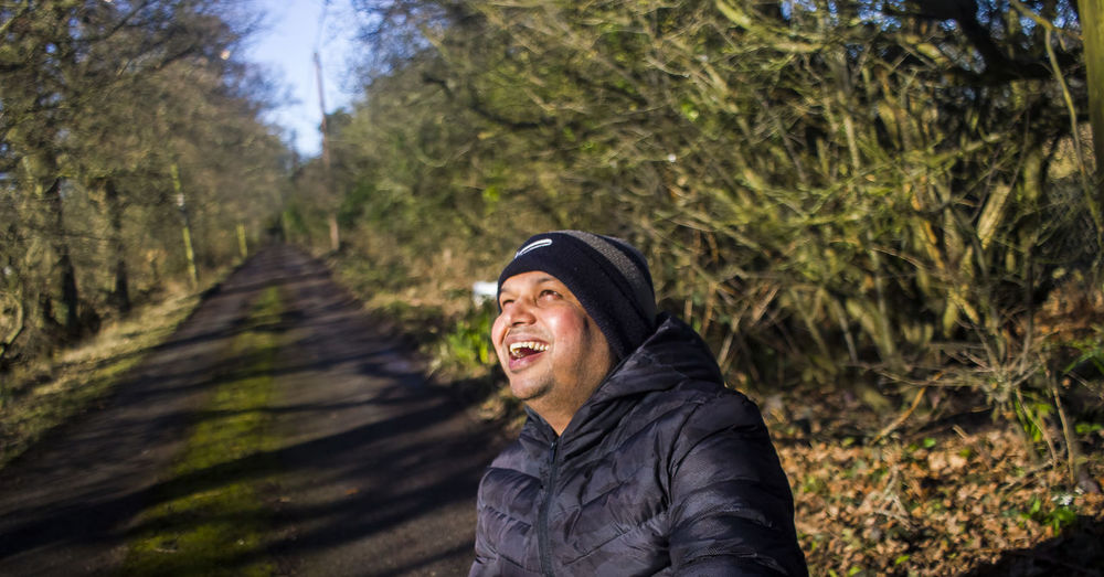 Man laughing against trees