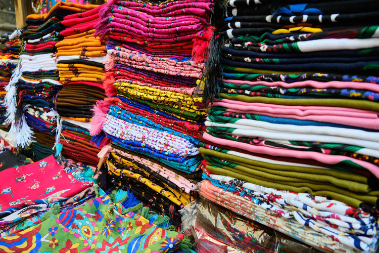 Colorful traditional middle eastern shawls folded at bazaar. multi-colored headscarfs