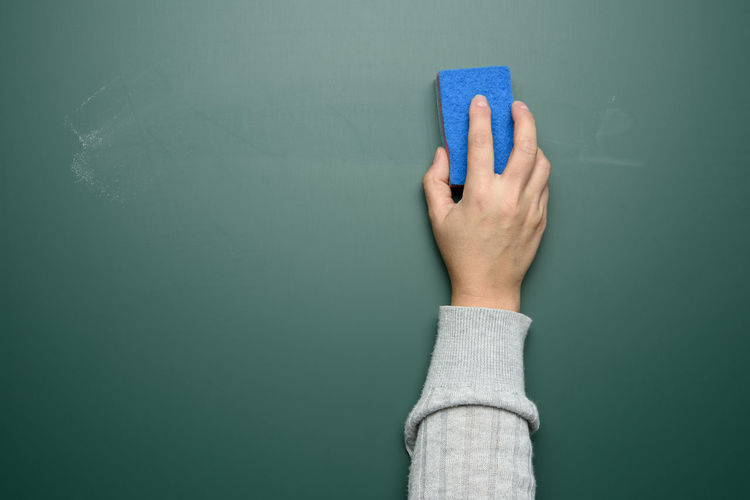 Cropped image of teacher holding duster against blackboard