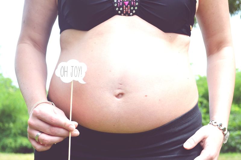 Midsection of pregnant woman holding thought bubble