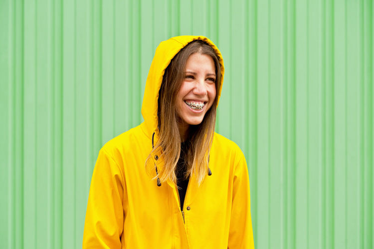 Portrait of young woman standing against wall