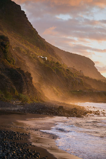 Scenic view of beach against cliff during sunset