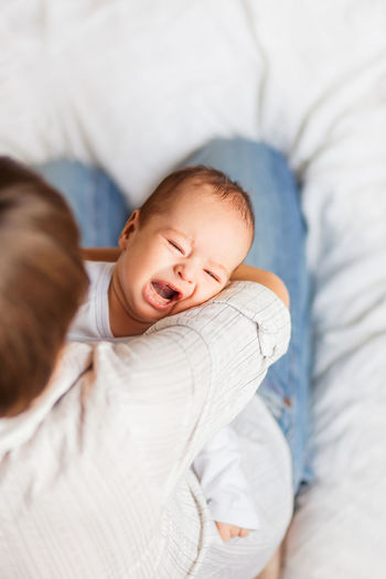 Woman holding a crying child. mother comforts her little son or daughter.