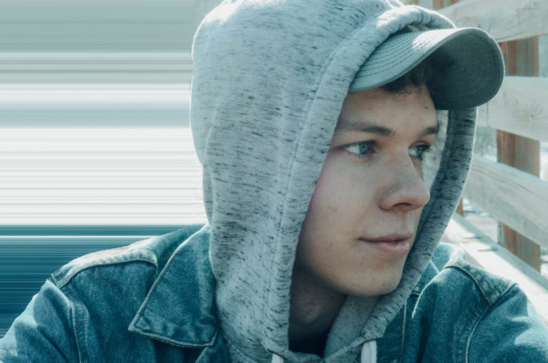 Close-up of young man wearing hood while looking away