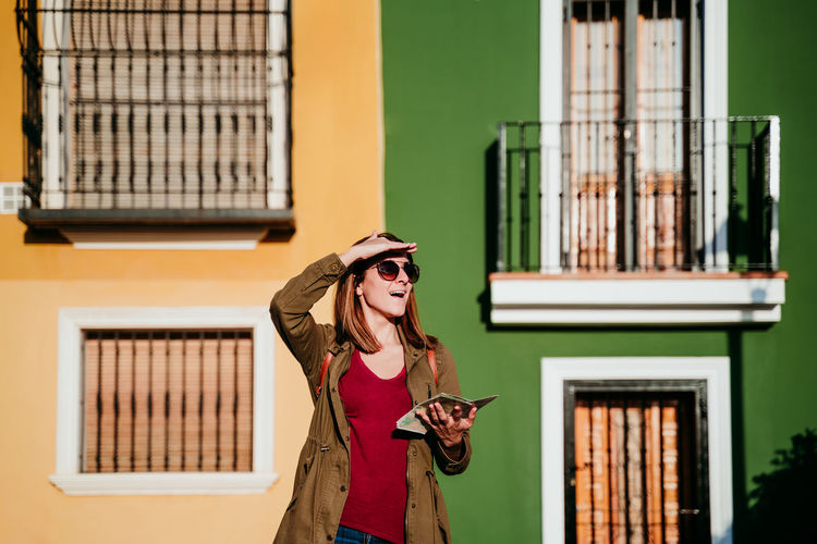 Woman wearing hat standing against building