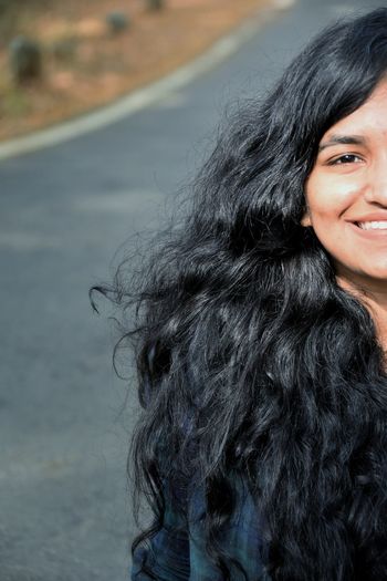 Portrait of smiling young woman with long hair on road