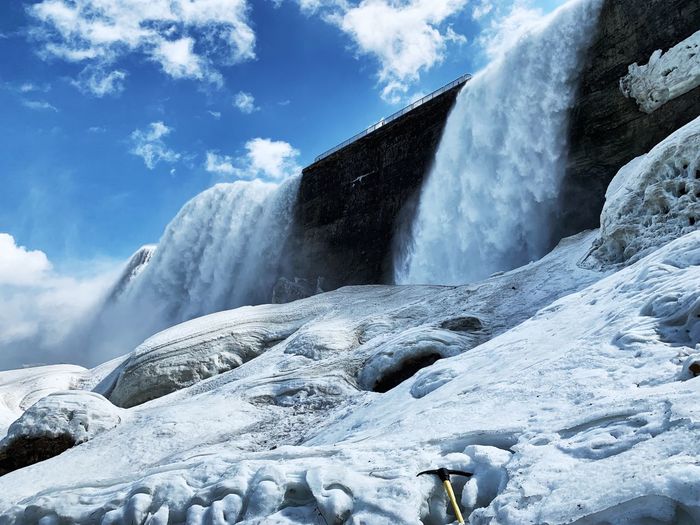 Scenic view of waterfall against snowcapped mountains during winter
