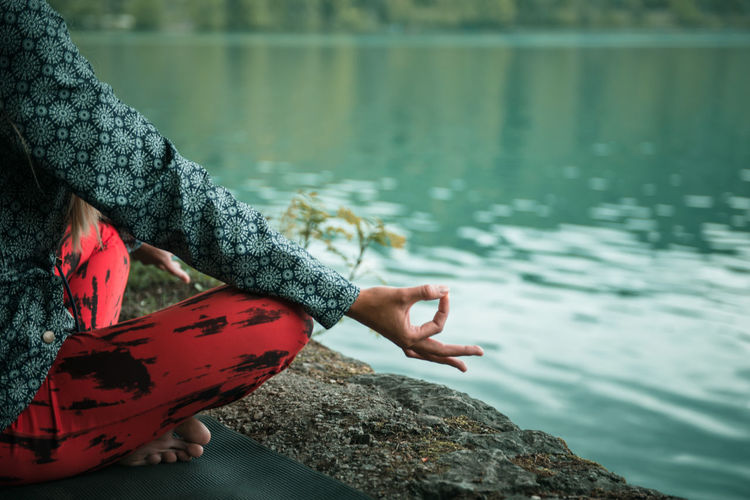 Low section of woman doing yoga on rock at lake