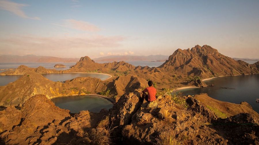 High angle view of man sitting on rock formation at padar island