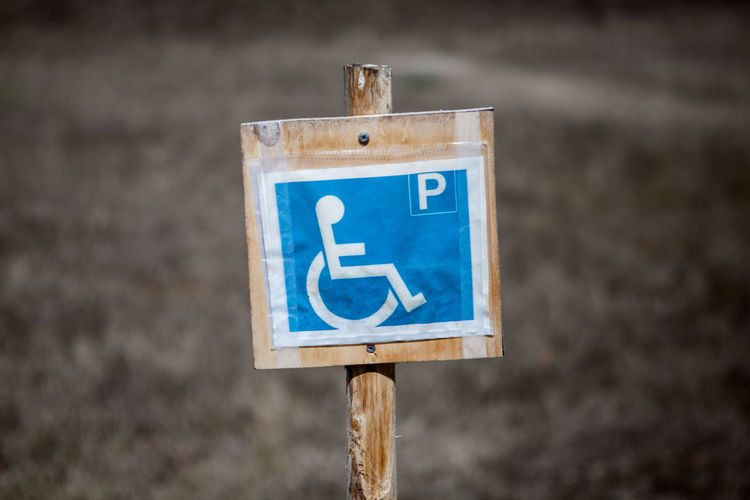 Close-up of blue disabled parking sign on wooden post