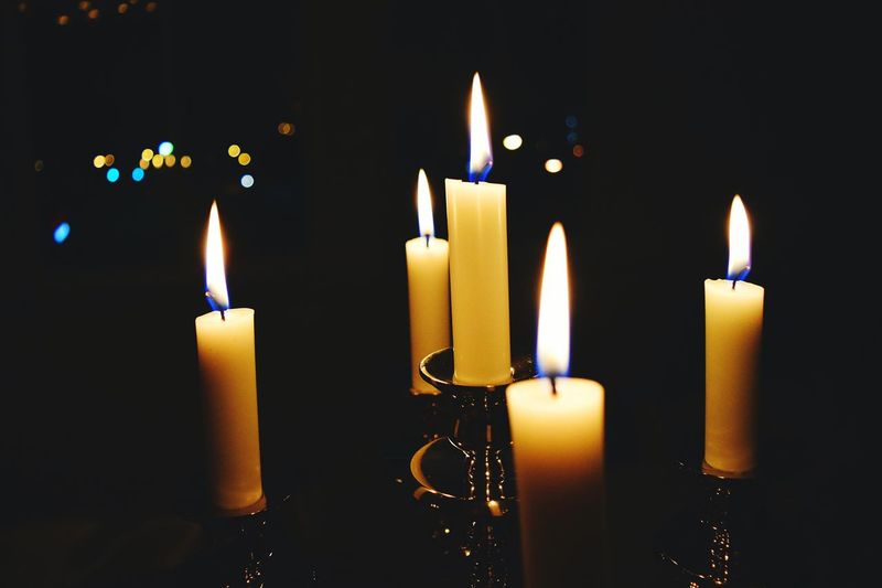 Close-up of burning candles on holder in dark