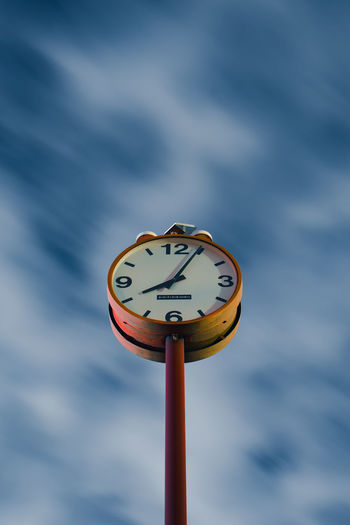Low angle view of clock against sky