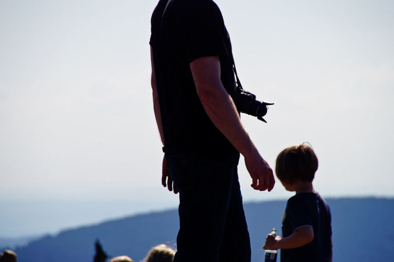 Midsection of man with camera against sky