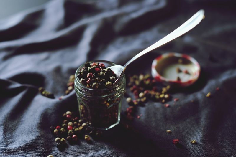 Close-up of black peppercorns in jar on fabric