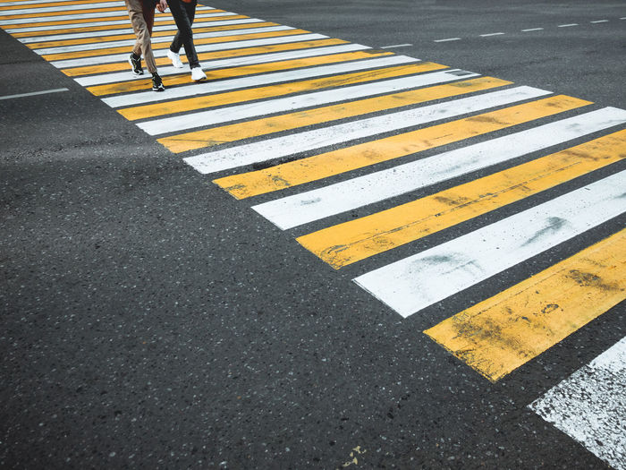 Two young man cross the road at a pedestrian crossing. zebra crossing on asphalt. city road marking.
