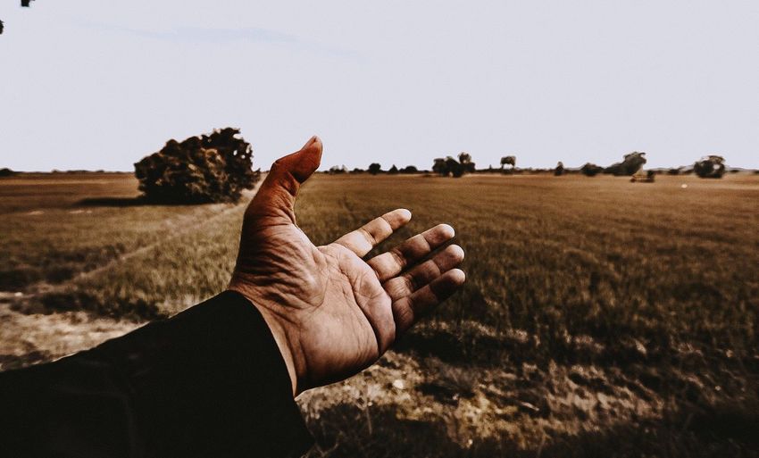 Cropped hand of man gesturing against landscape