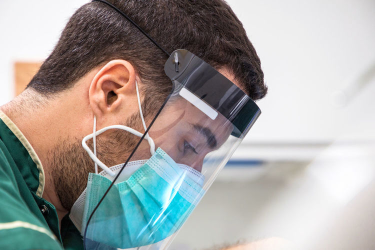 Side view of male doctor with face mask and face shield while working