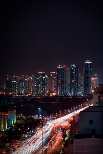 Illuminated city by buildings against sky at night, songdo, south korea