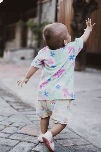 Rear view of baby girl standing on footpath