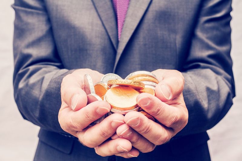 Midsection of businessman holding gold and silver coins