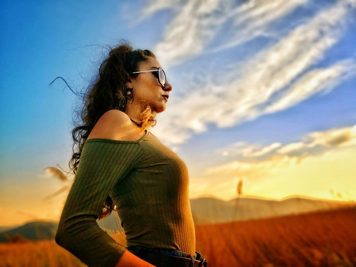 Low angle view of woman standing against sky during sunset