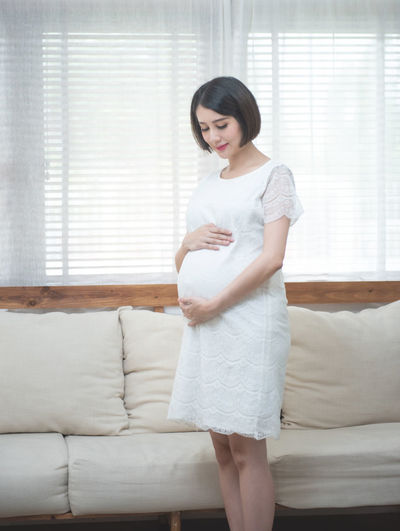 Pregnant woman holding stomach standing at home