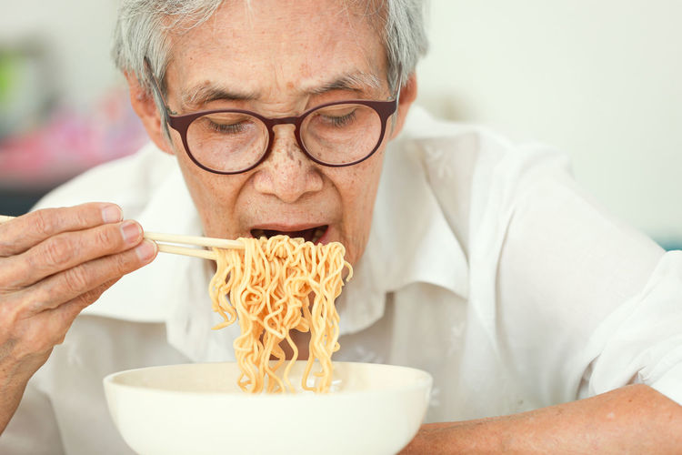 Senior woman eating noodles