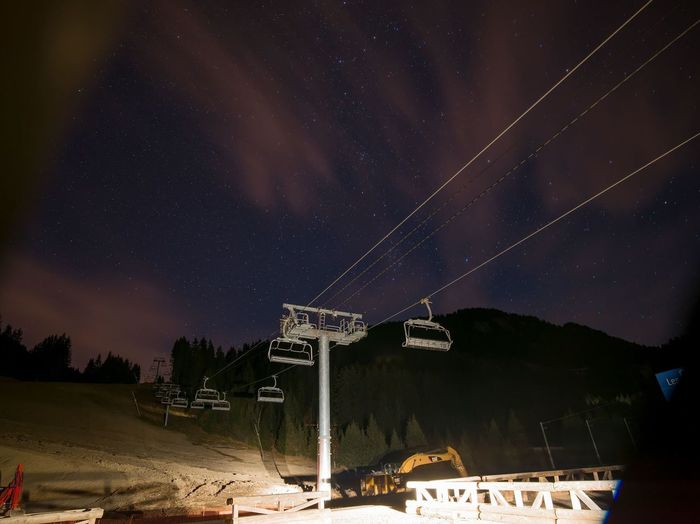 Low angle view of ski lifts over mountains against sky