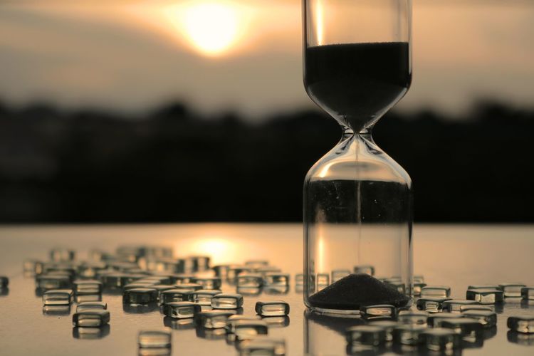 Close-up of hourglass on table during sunset