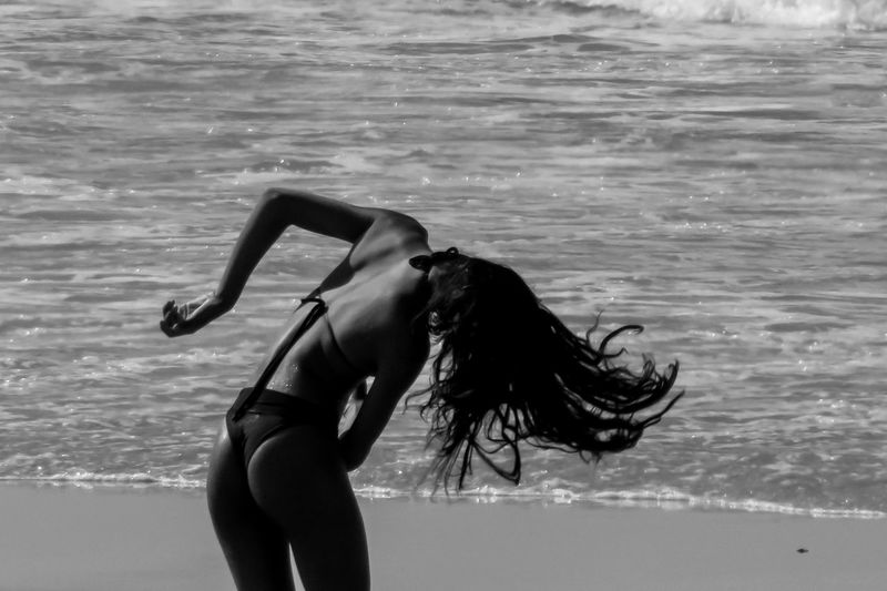 Rear view of woman tossing hair at beach
