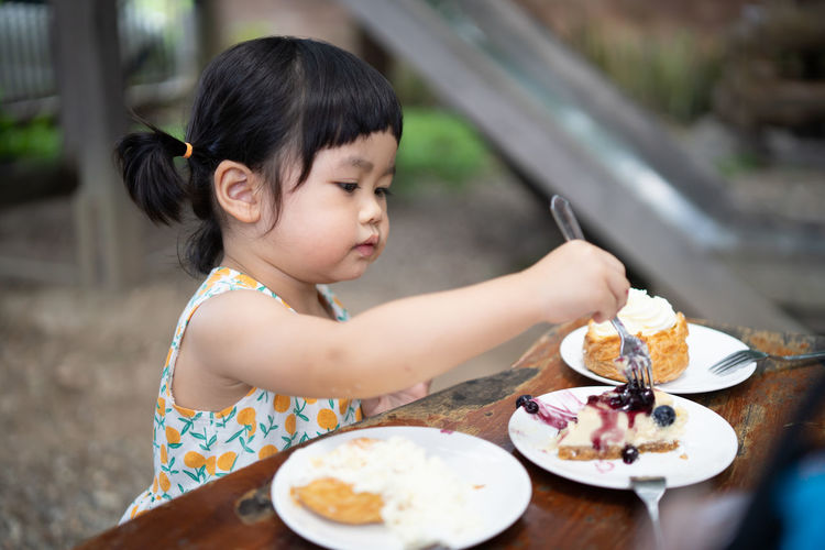 Girl holding ice cream in plate on table