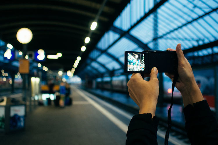 Cropped hands photographing at railroad station platform