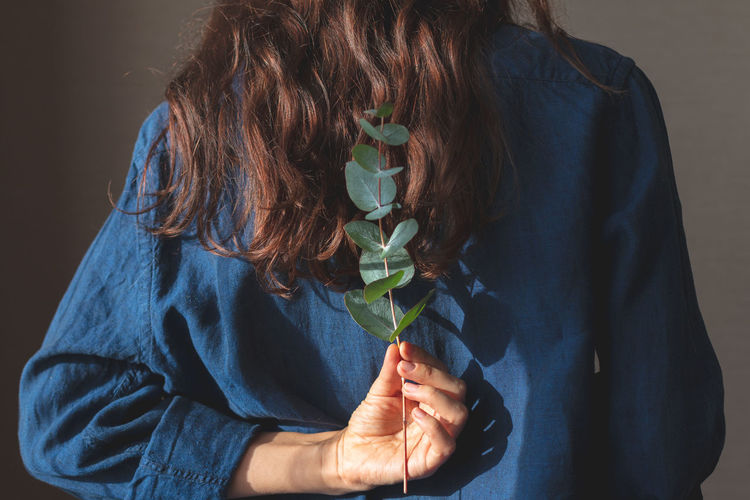 Midsection of woman holding leaves behind back