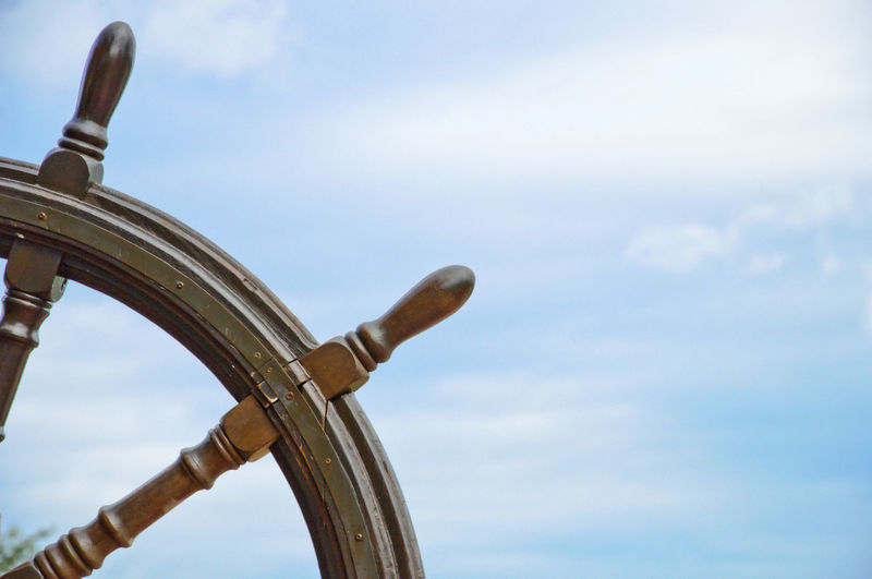 Close-up of boat driving wheel against sky