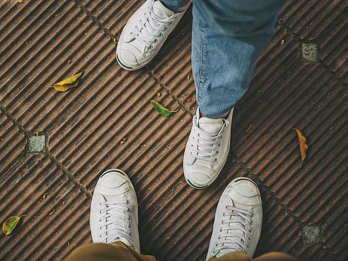 Low section of friends standing on footpath