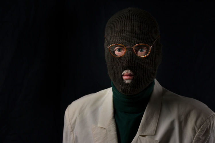 Portrait of burglar wearing mask against black background
