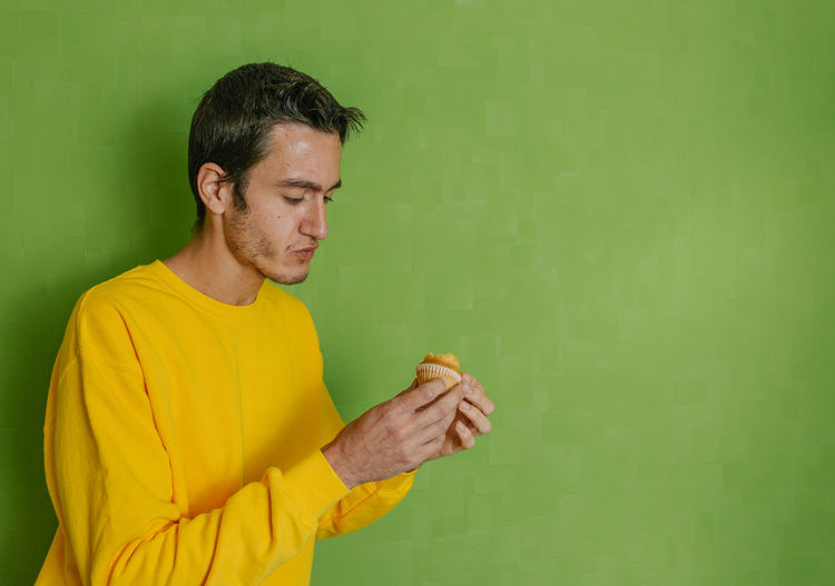 Man holding yellow while standing against wall