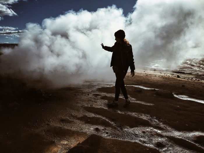 Full length of woman walking by geyser emitting smoke